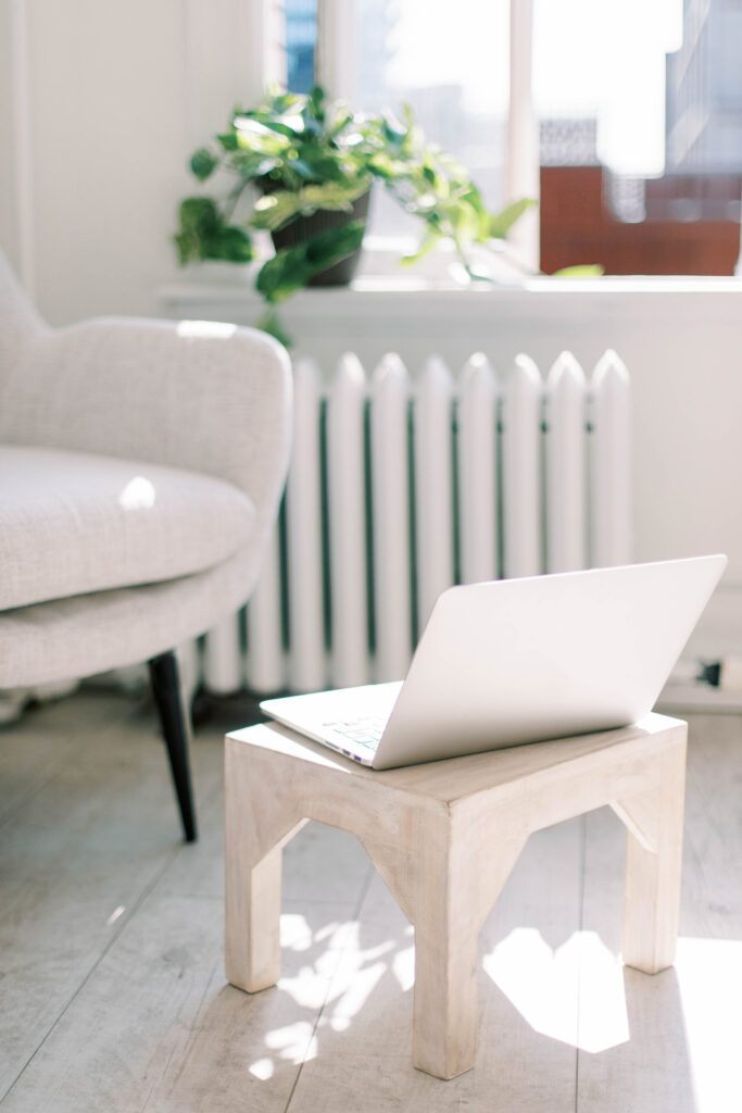 Laptop on small table in front of gray chair