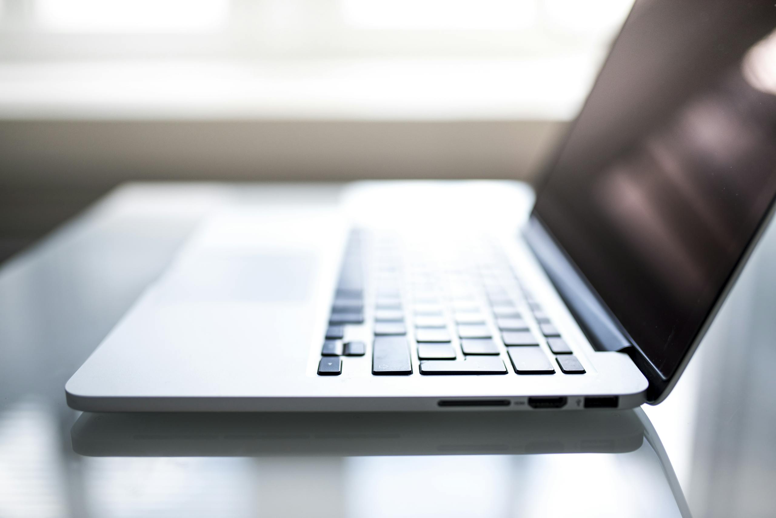 Elegant side view of a laptop on a glossy table with natural lighting indoors.